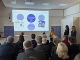 Veranstaltungsraum mit Publikum von hinten auf große Beamer-Leinwand mit Präsentation zur Kommunikation und Social Media Aktivitäten im Projekt #parentsonboard