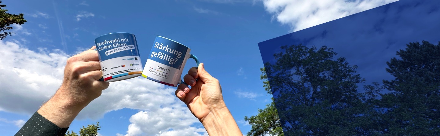 Zwei Hände die jeweils eine TalkCafé-Tasse vor dem blauen Himmel halten