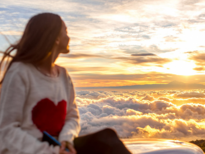 Mädchen sitzend das seitlich von oben auf eine Wolkendecke schaut